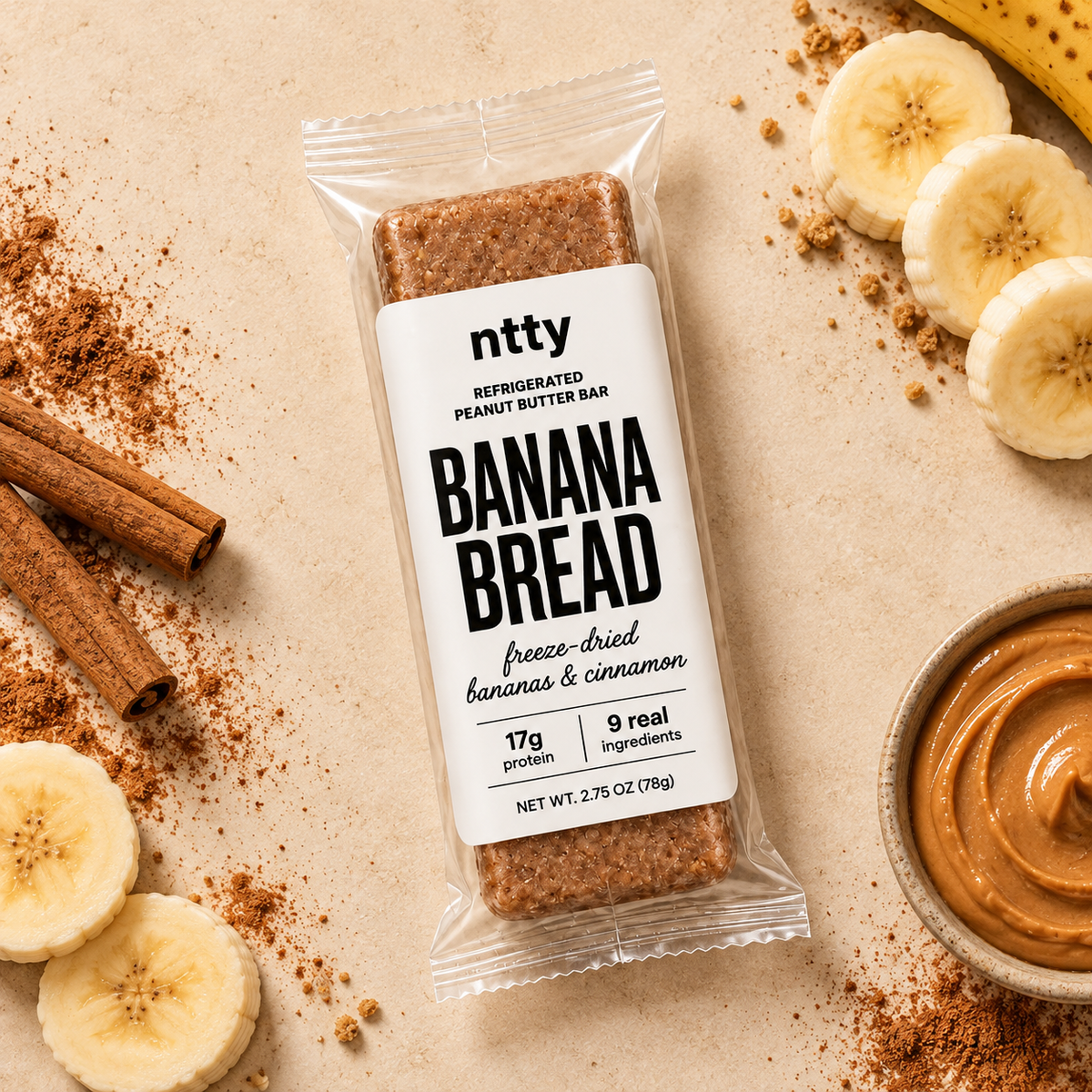ntty banana bread protein bar surrounded by a bowl of peanut butter, cinnamon, and bananas