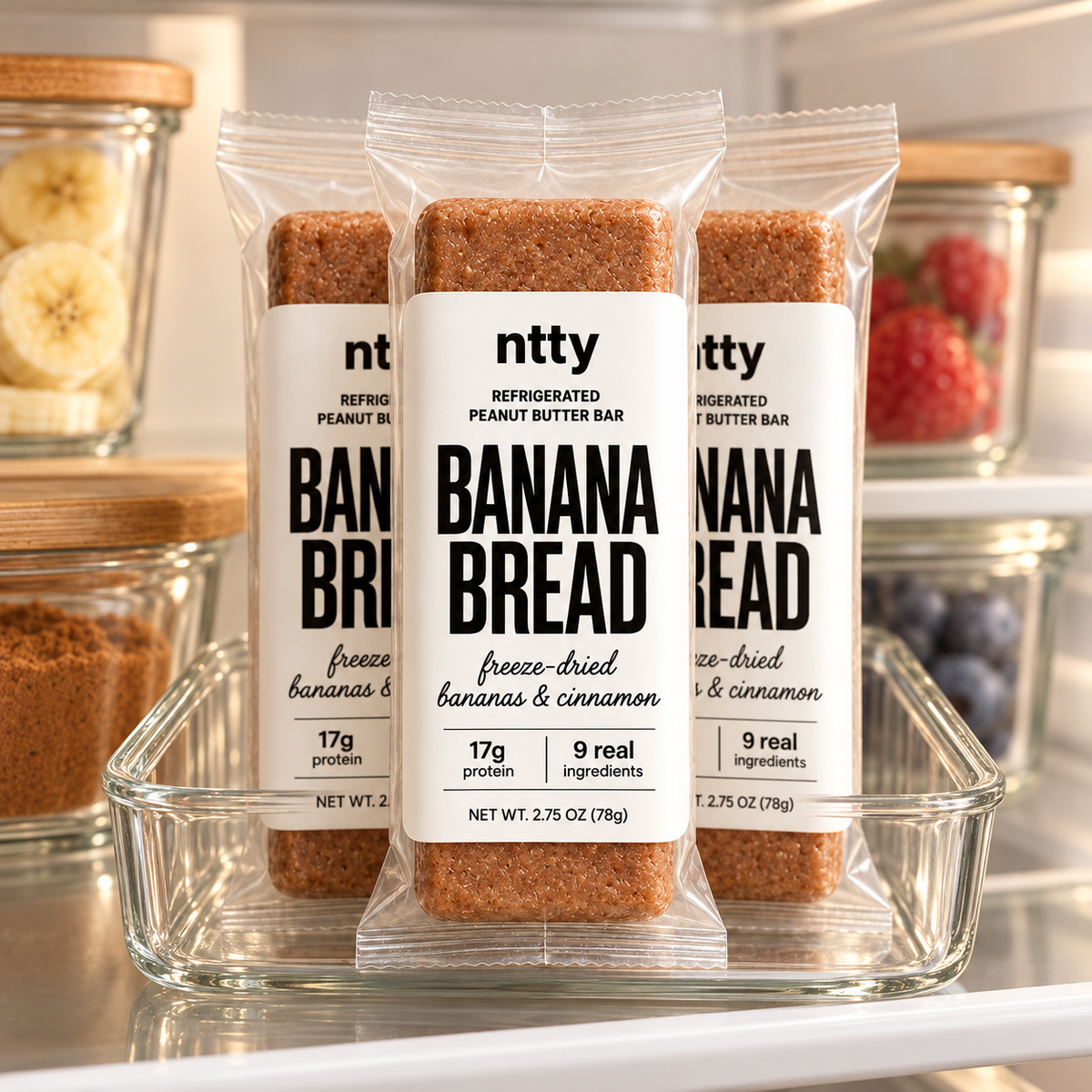 Three ntty banana bread protein bars in a clear glass tray on a refrigerator shelf