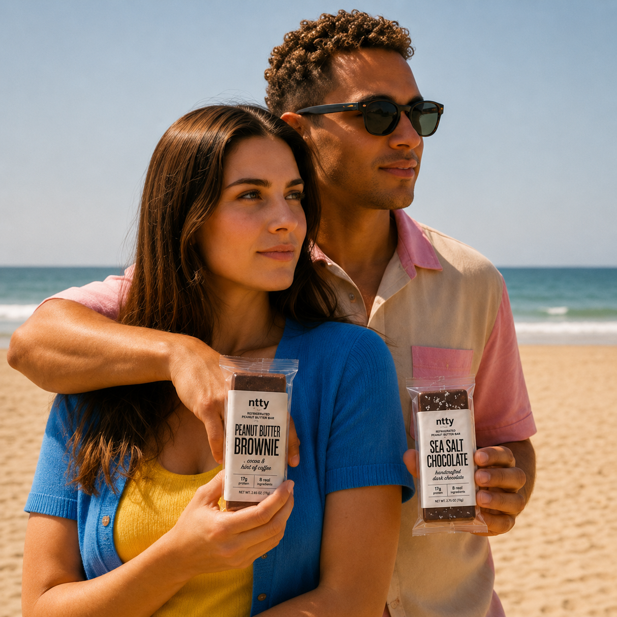Couple at the beach holding ntty peanut butter brownie and sea salt chocolate bars.