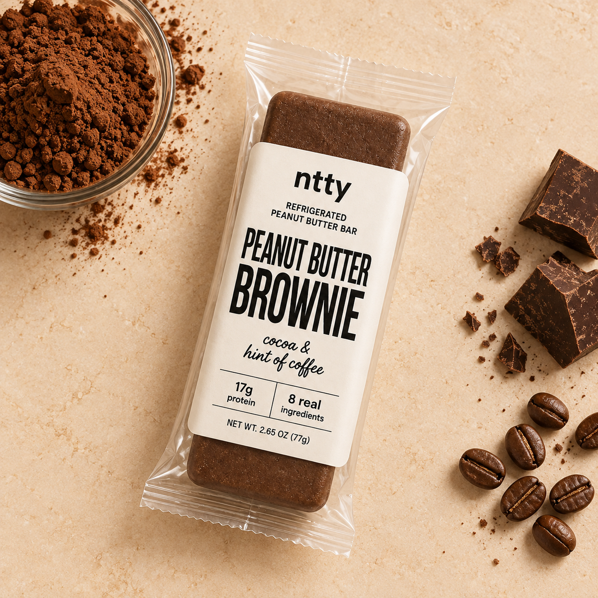 ntty brownie protein bar surrounded by a bowl of cocoa powder, chocolate and coffee beans