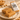 ntty Peanut Butter protein bar broken in half on a speckled plate, showing its soft, crumbly texture, with the wrapped bar behind it