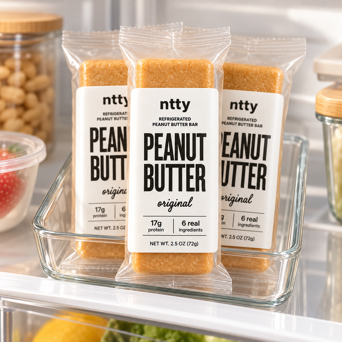 Three ntty Peanut Butter original protein bars in a clear glass tray on a refrigerator shelf