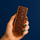 Hand holding an ntty Sea Salt Chocolate refrigerated peanut butter protein bar topped with dark chocolate and sea salt.