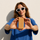 Woman holding an unwrapped ntty refrigerated peanut butter bar toward the camera.