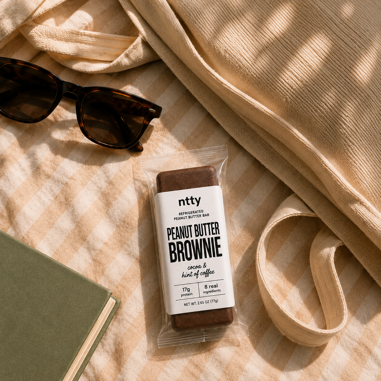 ntty peanut butter brownie bar on a blanket with sunglasses and a book.